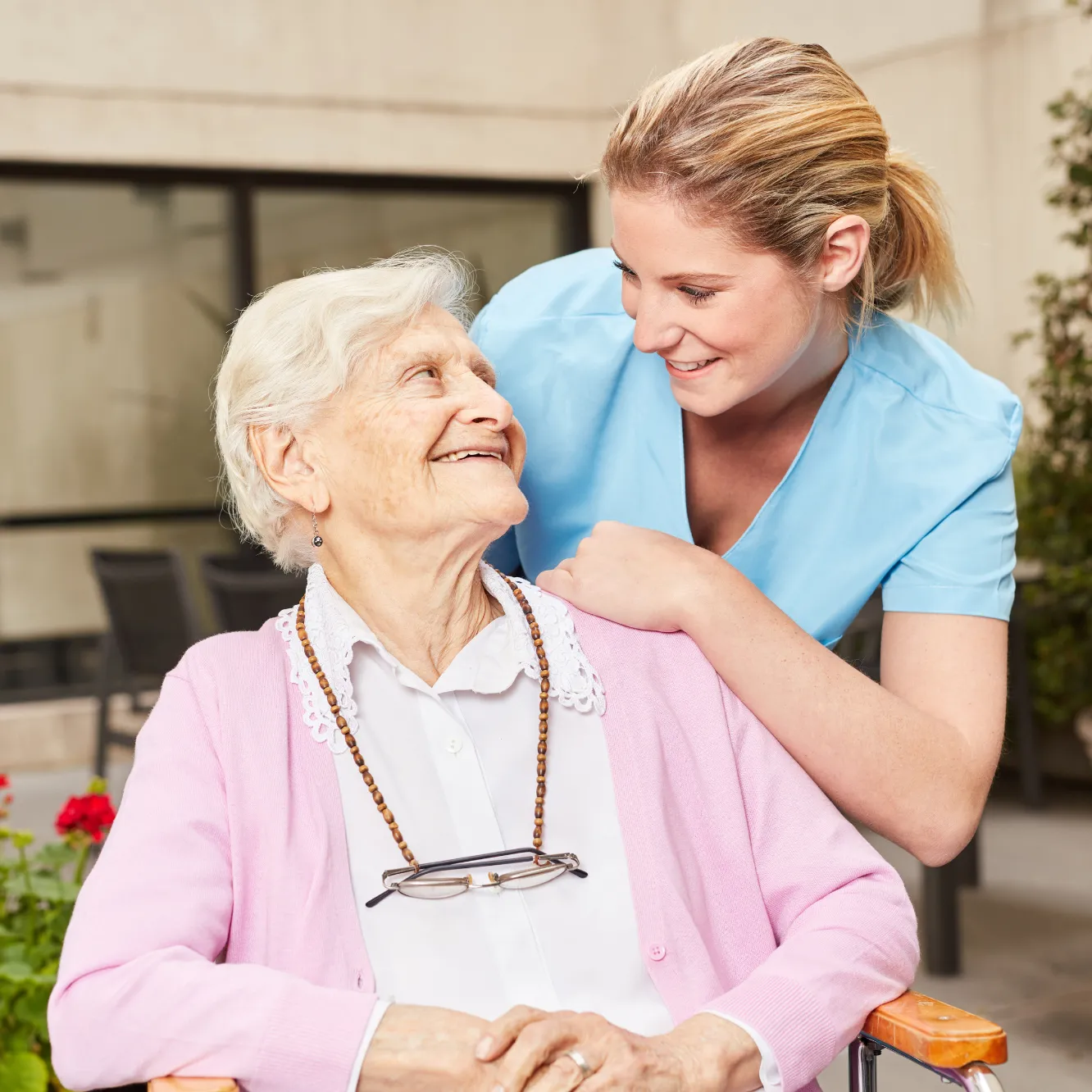 Caregiver smiling with elderly woman in wheelchair